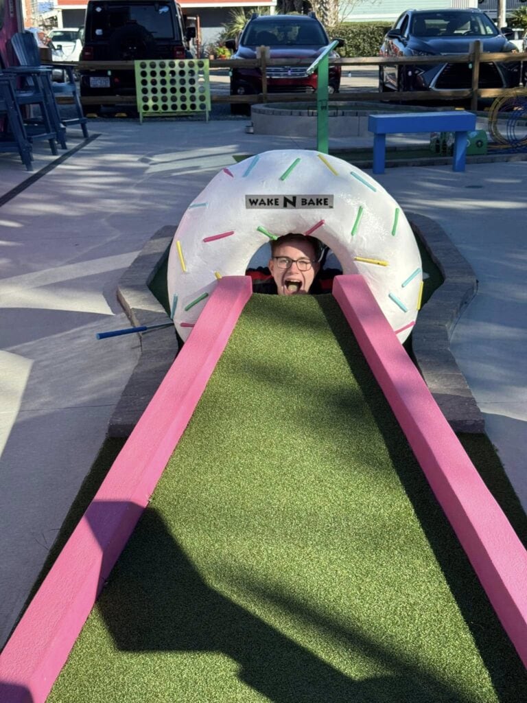 A colorful mini-golf course at Putter Pub near Kure Beach, NC, featuring a donut-shaped obstacle and a vibrant green playing surface.